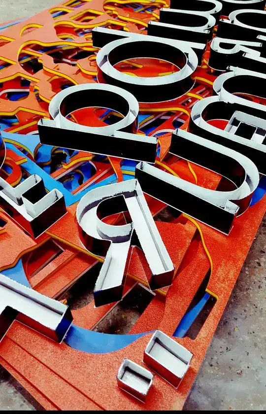 Letras caixa de metal sendo montadas sobre chapas recortadas na oficina